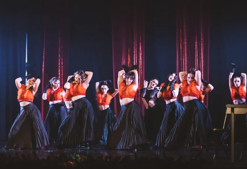 Ballerine in rosso e nero durante una coreografia, davanti al sipario
