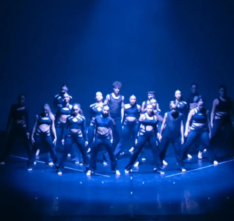 Un gruppo di ballerini sotto la luce blu del palco