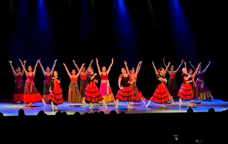 Ballerine in costume rosso e nero salutano il pubblico alla fine della coreografia