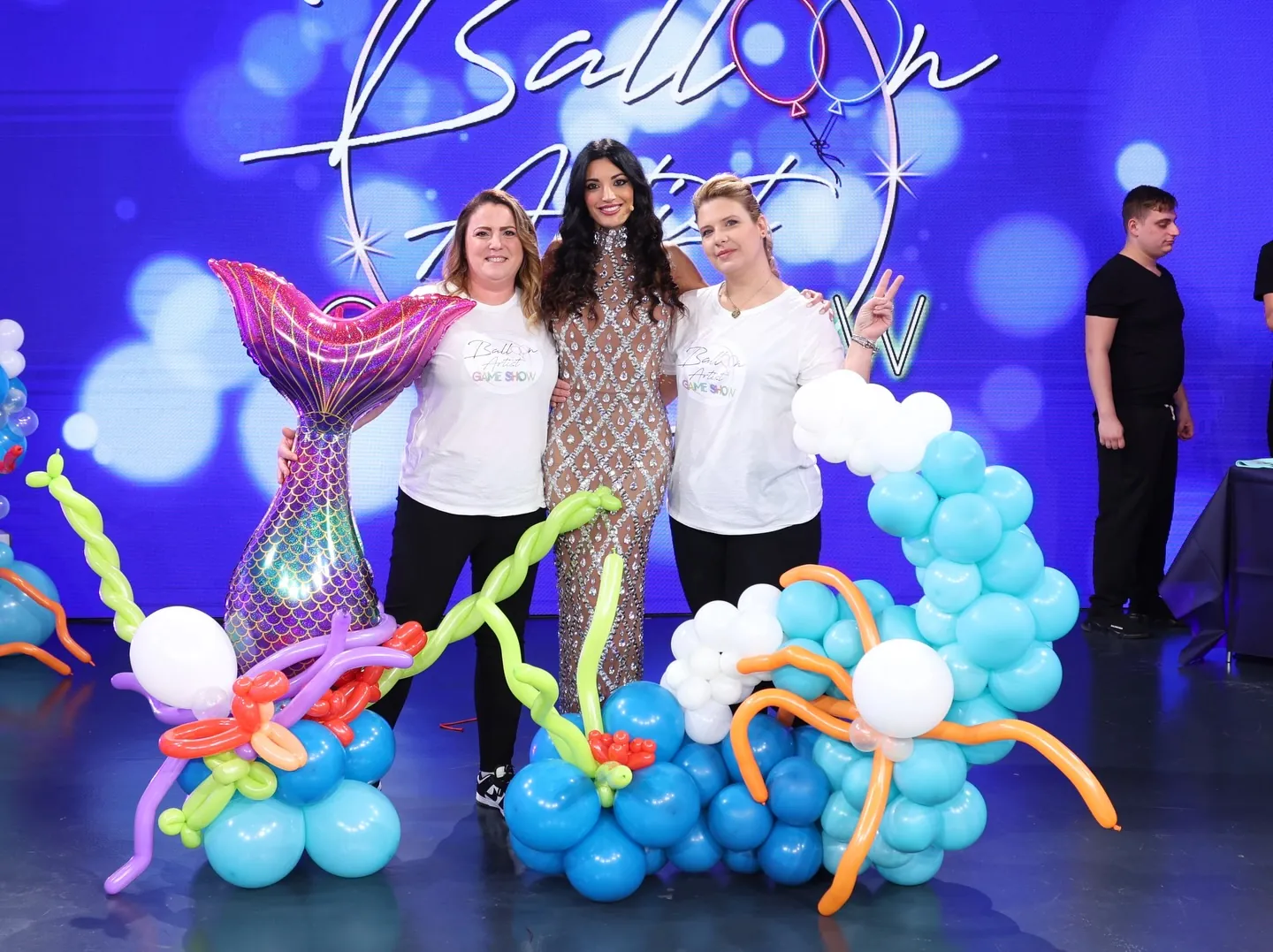 Una sirena e un fondale marino fatti di palloncini, con due artiste e la conduttrice sul set del programma