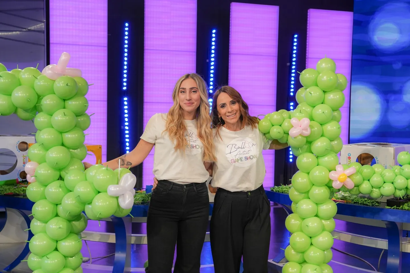 Due concorrenti accanto ai cactus di palloncini, sul set del programma