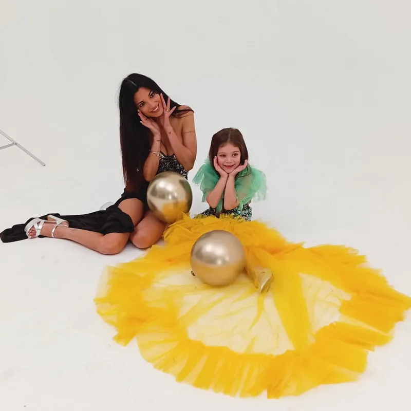 Una bambina e la sua insegnante, sedute su un grande abito giallo